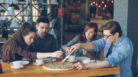 Friends sharing pizza; illustrative dining photography
